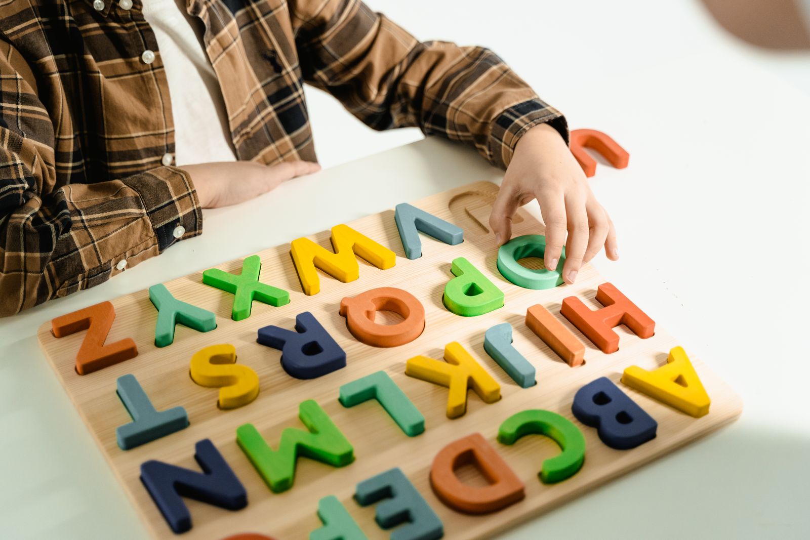Kind übt spielerisch mit bunten Buchstabensteinen